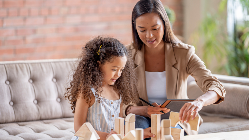 Therapist using play-based ABA therapy with a child building blocks to teach communication, social skills, and learning through play.